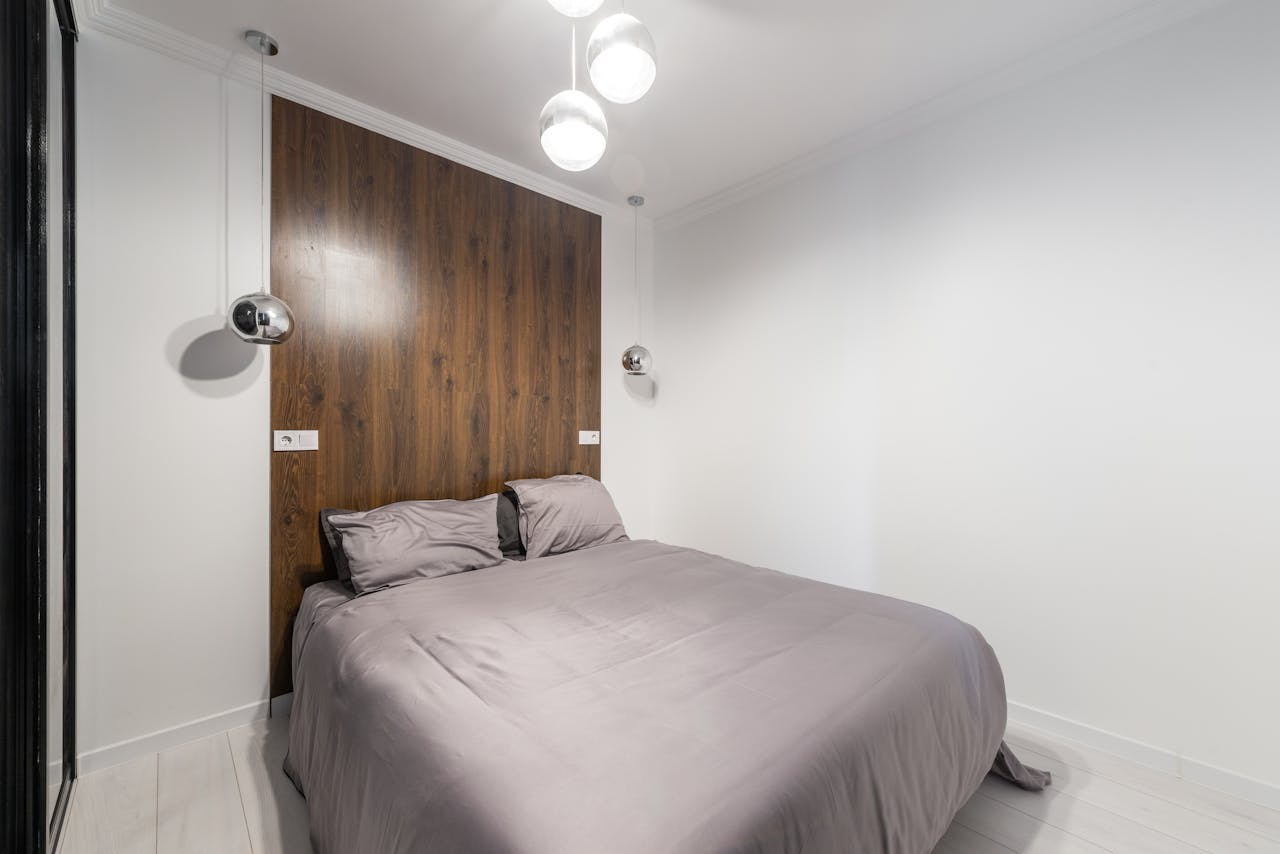 Contemporary bedroom with sleek design, wooden accents, and pendant lights.